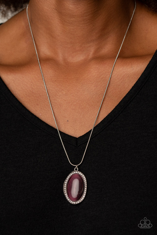 Encrusted with a ring of glittery white rhinestones, a wavy silver frame nestles around a glassy purple cat's eye stone. The dewy frame slides along a rounded silver snake chain, creating a glistening pendant below the collar. Features an adjustable clasp closure.

Sold as one individual necklace. Includes one pair of matching earrings.