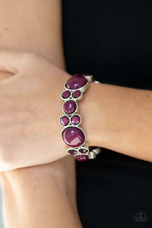 Infused with pairs of Magenta Purple rhinestones, mismatched Magenta Purple beaded silver frames are delicately threaded along stretchy bands around the wrist for a whimsical pop of color.

Sold as one individual bracelet.