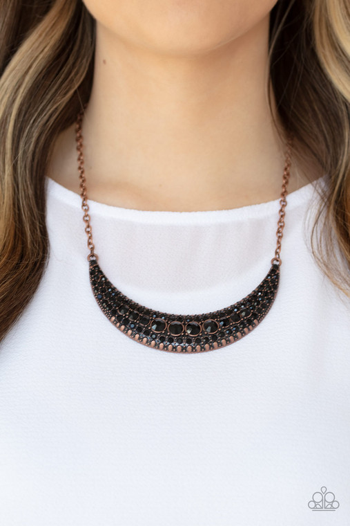 Varying in size, row after row of glittery black rhinestones are encrusted along the front of a studded half moon copper frame, creating a glittery statement below the collar. Features an adjustable clasp closure.

Sold as one individual necklace. Includes one pair of matching earrings.