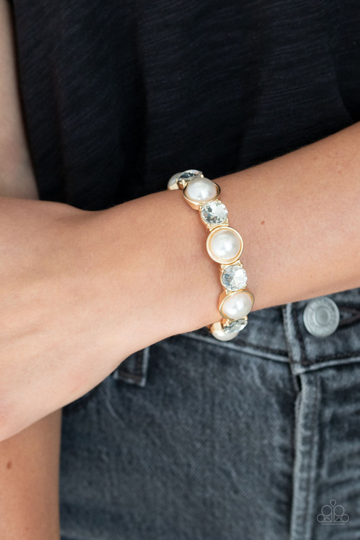 Featuring sleek gold fittings, bubbly white pearls and oversized white rhinestones are delicately threaded along stretchy bands around the wrist for a refined flair.

Sold as one individual bracelet.