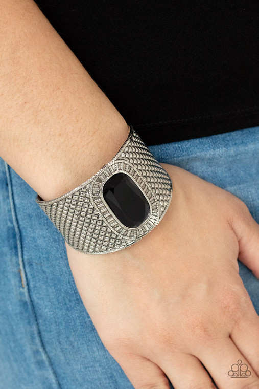 An ovsized black gem is pressed into the center of a thick silver cuff embossed in diamond-like textures, creating a bold tribal inspired centerpiece around the wrist.

Sold as one individual bracelet.