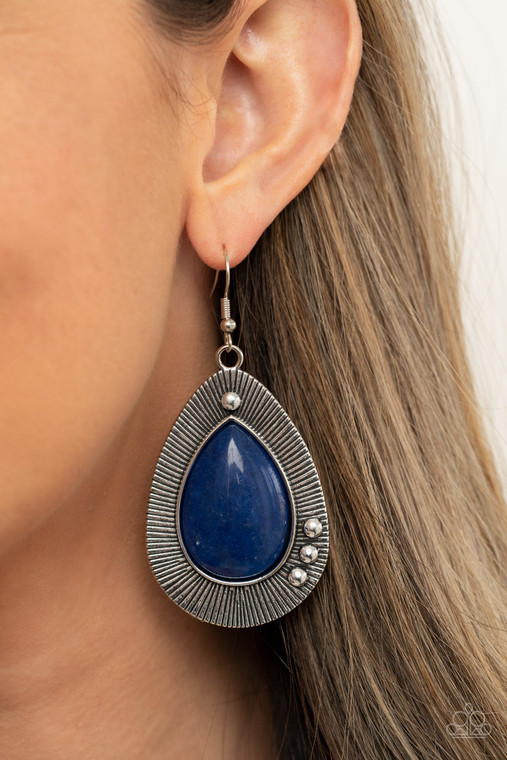 Chiseled into a tranquil teardrop, a shimmery French Blue stone bead is pressed into the center of a rustically studded silver frame radiating with antiqued detail for a southwestern flair. Earring attaches to a standard fishhook fitting.

Sold as one pair of earrings.