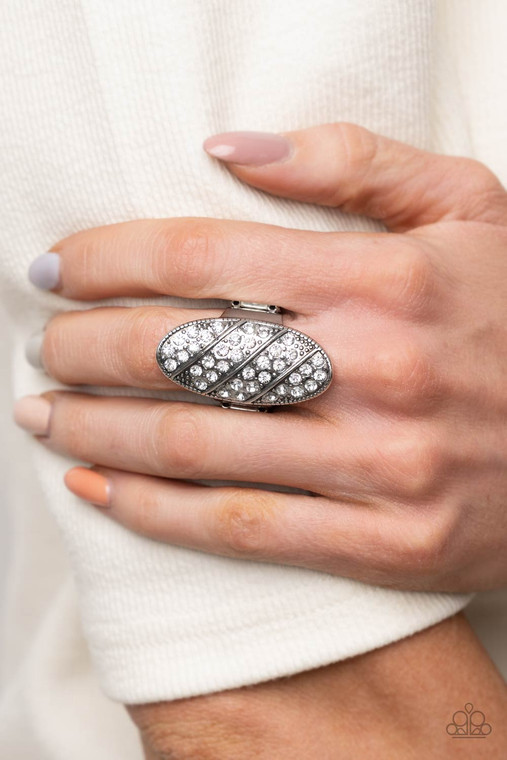 Rows of glassy white rhinestones slant across a stretched oval frame dotted in silver studs, creating a dramatic centerpiece atop the finger. Features a stretchy band for a flexible fit.

Sold as one individual ring.