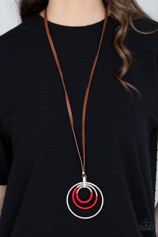 An impressive set of thick silver hoops is held together in concentric fashion by a strong silver fitting. Boldly wrapped bright red thread accents two hoops as the hefty pendant suspends from a lengthened brown leather cord in a hypnotic display. Features an adjustable clasp closure

Sold as one individual necklace. Includes one pair of matching earrings.
