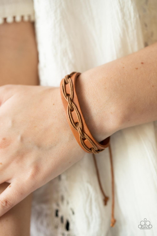 Brown cording is interwoven across the top of a light brown leather band creating an edgy crisscrossed texture around the wrist. Features an adjustable sliding knot closure.

Sold as one individual bracelet.