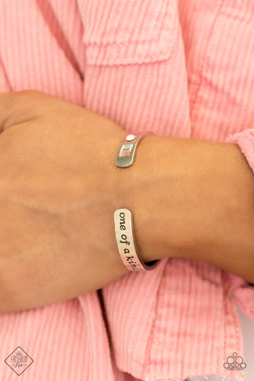 A minimalistic silver bar etched with the words, “one of a kind” on one end and embellished with a dainty rhinestone and pastel gems on the other, curves into a simple cuff around the wrist.

Sold as one individual bracelet.