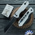 Heretic Knives Jinn Manual, Battle Black Magnacut Blade, Blizzardworn Aluminum Handles