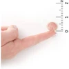 Probiotic chewable on a fingertip beside an inch ruler