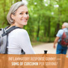 Smiling woman hiking in a forest, turmeric gummy with 50 mg curcumin per serving