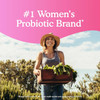 Woman holding a crate of vegetables in a field, women's probiotic brand graphic