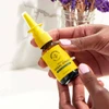 Hands holding the propolis nasal spray in front of flowers