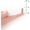 Single capsule on a fingertip beside a ruler for size