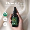 Hand holding the dropper bottle with organic and non-GMO badges