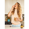 Woman in a kitchen taking an Everyday 10 capsule with water