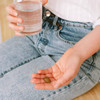 Hand holding Vata Digest tablets and a glass of water