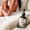 Sleep Easy Oil bottle on a bedside table with feet resting on bed