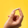 Hand holding a Serotonin Brain Food capsule on a yellow background