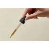 Hand holding glass dropper of brown olive leaf extract