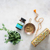Memory bottle with mala beads brass bowl and fresh herbs flat lay