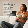 Smiling woman on a sofa holding a bowl, healthy gut, happy you graphic