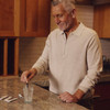 Older man in kitchen with Tru Niagen stick pack and glass of water graphic