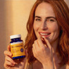Woman taking a capsule holding a Tru Niagen Immune bottle