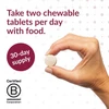 Hand holding a chewable tablet with take two per day text