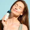 Woman holding the Barrier Pro Serum Spray to her neck