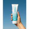 Hand holding the Coola Mineral Body Lotion SPF 50 tube