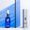 iS Clinical Active Serum blue bottle and Youth Complex silver bottle by a blue panel