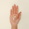 Hand holding the three Perelel vitamin trio capsules