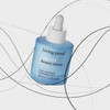 Scalp Care Density Serum bottle floating among dark hair strands