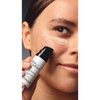 Woman holding dose of wisdom eye cream with under-eye swipe