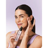 Woman holding lift and firm serum with cream on cheek