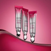 Three eye cream tubes standing on a pink wave