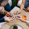 Friends toasting with ZBiotics bottles around a table