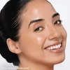 Smiling model with dark hair wearing Cream Bronze Stick in Warm Glow
