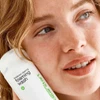 Smiling woman holding the Clear Start foaming wash to her cheek