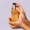 Hands holding epionce Lytic Gel Cleanser bottle on lavender background