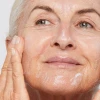 Mature model applying Dermalogica Super Rich Repair moisturizer to cheek