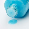 Blue liquid pouring from the open bottle