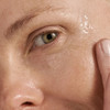 Close-up of model's eye area with fingertip applying Dermalogica MultiVitamin Power Firm