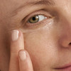 Close-up of fingertip applying eye cream under the eye
