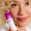 Smiling woman holding the Clear Start booster near her face