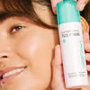 Smiling woman holding the Fizz Mask bottle to her cheek