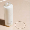 Uncapped Remedy bottle with a drop of oil on a beige surface