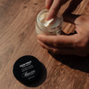 Fingers scooping Baxter of California Cream Pomade from the jar