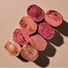 Pressed Color Balm shades in pinks, berries and bronzes on a pink background