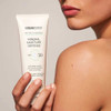 Hand holding the tube against a bare shoulder