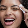 Smiling model wiping face with cotton pad of Obagi CLENZIderm Pore Therapy